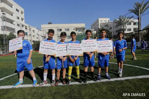 Palestinian boys hold placards demanding for end the siege during a training season for football school at Al Jazeera club in Gaza city, on July 26, 2016. Photo by Mohammed Asad