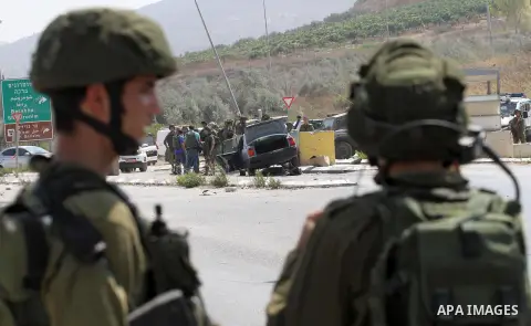 Israeli soldiers gather next to a vehicle belonging to a Palestinian man after he reportedly charged it into a group of soldiers at the Israeli army Hawara checkpoint near the city of Nablus in the occupied West Bank on...