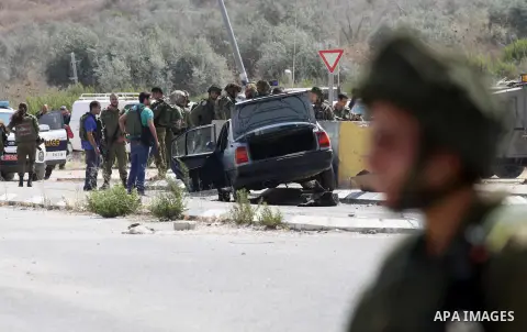 Israeli soldiers gather next to a vehicle belonging to a Palestinian man after he reportedly charged it into a group of soldiers at the Israeli army Hawara checkpoint near the city of Nablus in the occupied West Bank on...