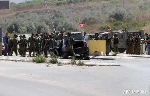 Israeli soldiers gather next to a vehicle belonging to a Palestinian man after he reportedly charged it into a group of soldiers at the Israeli army Hawara checkpoint near the city of Nablus in the occupied West Bank on...