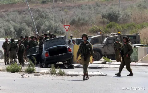 Israeli soldiers gather next to a vehicle belonging to a Palestinian man after he reportedly charged it into a group of soldiers at the Israeli army Hawara checkpoint near the city of Nablus in the occupied West Bank on...