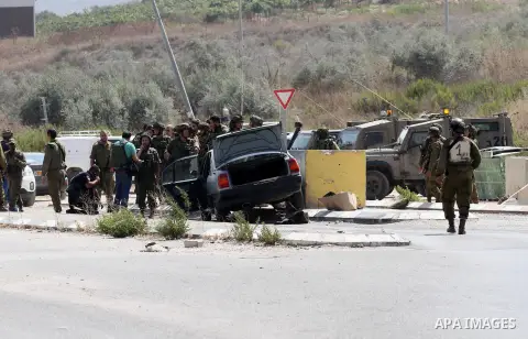 Israeli soldiers gather next to a vehicle belonging to a Palestinian man after he reportedly charged it into a group of soldiers at the Israeli army Hawara checkpoint near the city of Nablus in the occupied West Bank on...