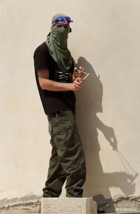 A Palestinian protestor uses a slingshot to hurl stones towards Israeli security forces during clashes following the weekly demonstration against the expropriation of Palestinian land by Israel in the village of Kfar Qad...