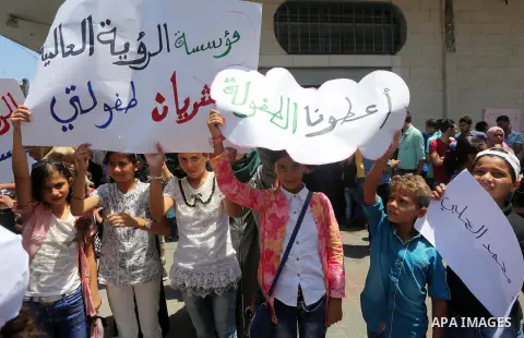 Palestinian demonstrators hold posters of Mohammad El Halabi, World Vision's manager of operations in Gaza who was accused by Israel of funnelling millions of dollars in aid money to Hamas, during a protest in solidarity...