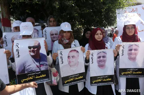Palestinian demonstrators hold posters of Mohammad El Halabi, World Vision's manager of operations in Gaza who was accused by Israel of funnelling millions of dollars in aid money to Hamas, during a protest in solidarity...