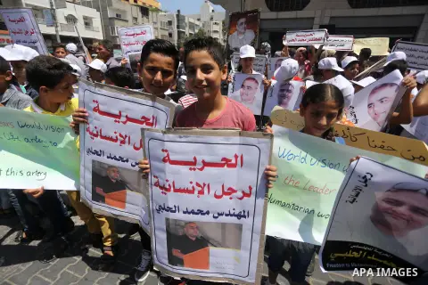 Palestinian demonstrators hold posters of Mohammad El Halabi, World Vision's manager of operations in Gaza who was accused by Israel of funnelling millions of dollars in aid money to Hamas, during a protest in solidarity...