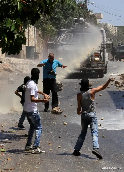 Palestinian protesters hurl stones towards an Israeli security forces vehicle spraying a foul-smelling water known as "skunk" during clashes following a weekly demonstration against the expropriation of Palestinian land...