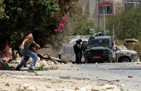 A Palestinian protester hurls stones towards Israeli security forces during clashes following a weekly demonstration against the expropriation of Palestinian land by Israel on August 12, 2016, in the village of Kfar Qadd...