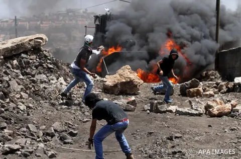 Palestinian protesters hurl stones toward an Israeli military bulldozer during clashes with Israeli security forces following a weekly demonstration against the expropriation of Palestinian land by Israel on August 12, 2...