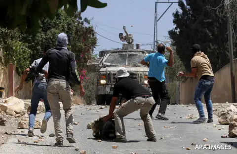 Palestinian protesters hurl stones towards an Israeli security forces vehicle spraying a foul-smelling water known as "skunk" during clashes following a weekly demonstration against the expropriation of Palestinian land...