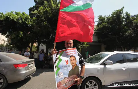 Palestinians hold posters against administrative detention and in support of Palestinian prisoner Bilal Kayed (portrait), who has been fasting for almost two months over his detention without trial, in Gaza city, on Augu...