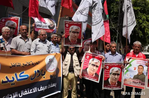 Palestinians hold posters against administrative detention and in support of Palestinian prisoner Bilal Kayed (portrait), who has been fasting for almost two months over his detention without trial, in Gaza city, on Augu...