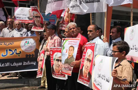 Palestinians hold posters against administrative detention and in support of Palestinian prisoner Bilal Kayed (portrait), who has been fasting for almost two months over his detention without trial, in Gaza city, on Augu...