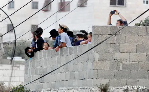 Israeli settlers gather at a roof visit the Jewish shrine of Atnaeil Ben Kinaz on August 14,2016 in a Palestinian neighbourhood of the divided West Bank city of Hebron. Orthodox Jews mark on August 14 2016 the annual Tis...