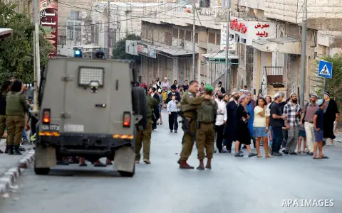 Israeli soldiers stand guard as Israeli settlers walk on a street in a Palestinian neighbourhood in the divided West Bank city of Hebron as they are heading to the Jewish shrine of Atnaeil Ben Kinaz on August 14,2016. Or...