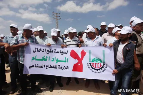 Palestinian traders hold banners during a protest against the Israeli authorities to withdraw permits for some of the traders and to prevent their entry into the West Bank, in front of the Erez crossing point with Israel...