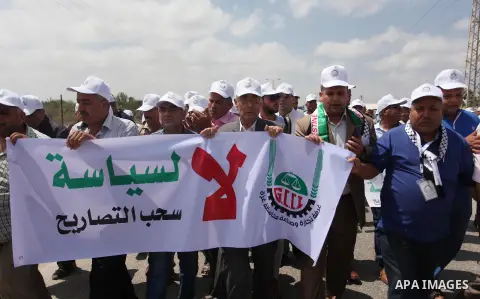 Palestinian traders hold banners during a protest against the Israeli authorities to withdraw permits for some of the traders and to prevent their entry into the West Bank, in front of the Erez crossing point with Israel...