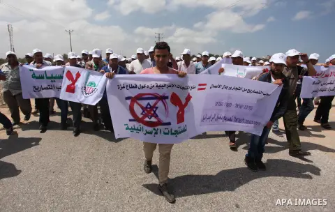 Palestinian traders hold banners during a protest against the Israeli authorities to withdraw permits for some of the traders and to prevent their entry into the West Bank, in front of the Erez crossing point with Israel...