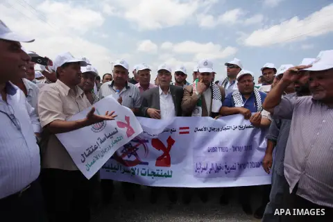 Palestinian traders hold banners during a protest against the Israeli authorities to withdraw permits for some of the traders and to prevent their entry into the West Bank, in front of the Erez crossing point with Israel...