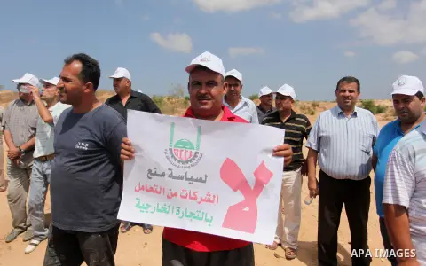 Palestinian traders hold banners during a protest against the Israeli authorities to withdraw permits for some of the traders and to prevent their entry into the West Bank, in front of the Erez crossing point with Israel...