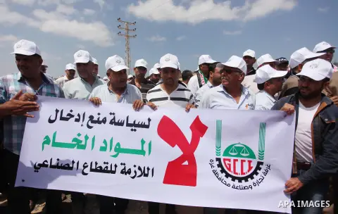 Palestinian traders hold banners during a protest against the Israeli authorities to withdraw permits for some of the traders and to prevent their entry into the West Bank, in front of the Erez crossing point with Israel...