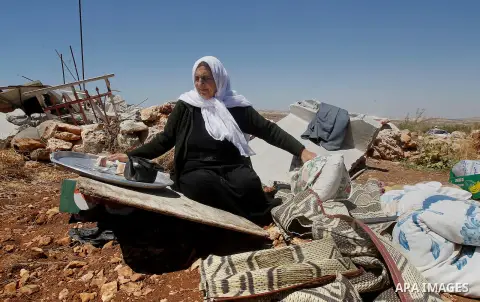 A Palestinian woman searches for her belongings after Israeli troops demolished her house in the West Bank village of Saeer, near Hebron August 16, 2016. Photo by Wisam Hashlamoun