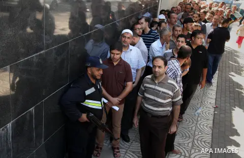 Employees of former Palestinian government in Gaza Strip wait to receive their salaries at a Post Office in Gaza city on August 17, 2016. The Emir of Qatar, Sheikh Tamim bin Hamad al-Thani, has ordered paying a total of...