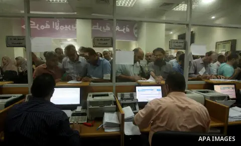 Employees of former Palestinian government in Gaza Strip wait to receive their salaries at a Post Office in Gaza city on August 17, 2016. The Emir of Qatar, Sheikh Tamim bin Hamad al-Thani, has ordered paying a total of...