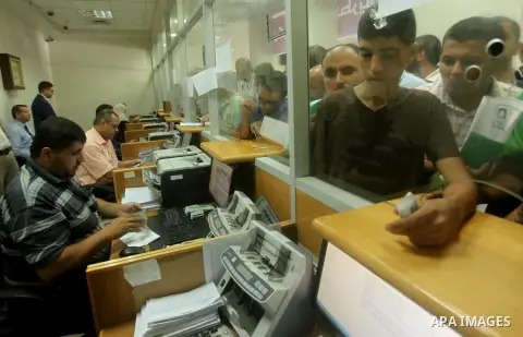 Employees of former Palestinian government in Gaza Strip wait to receive their salaries at a Post Office in Gaza city on August 17, 2016. The Emir of Qatar, Sheikh Tamim bin Hamad al-Thani, has ordered paying a total of...