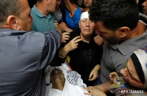 Relatives mourn next to the body of Palestinian Mohammed Abu Hashash, who was shot dead the day before during clashes with Israeli forces, before his funeral on August 17, 2016 in the al-Fawwar Palestinian refugee camp,...