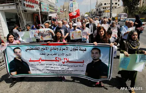 Palestinians hold posters against administrative detention and in support of Palestinian prisoner Bilal Kayed (portrait), who has been fasting for almost two months over his detention without trial, in the West Bank city...