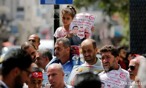 Palestinians hold posters against administrative detention and in support of Palestinian prisoner Bilal Kayed (portrait), who has been fasting for almost two months over his detention without trial, in the West Bank city...