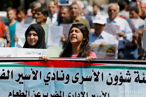 Palestinians hold posters against administrative detention and in support of Palestinian prisoner Bilal Kayed (portrait), who has been fasting for almost two months over his detention without trial, in the West Bank city...