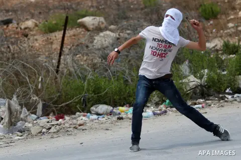 A Palestinian protester throws back a tear gas canister fired by Israeli troops during clashes following a protest in solidarity with Palestinian prisoners held in Israeli jails, near Israel's Ofer Prison near the West B...