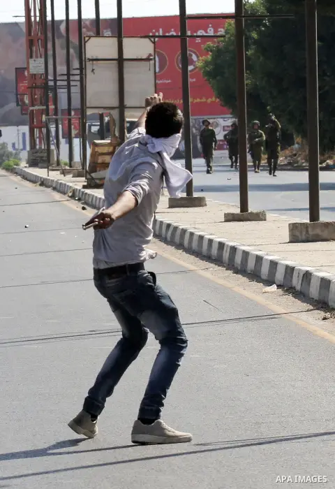 A Palestinian protester hurls stones towards Israeli troops during clashes following a protest in solidarity with Palestinian prisoners held in Israeli jails, at the Hawara checkpoint near the West Bank city of Nablus on...