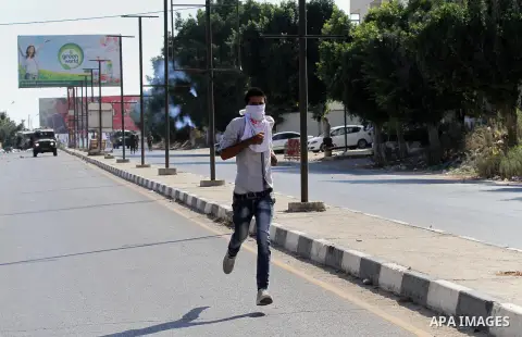 A Palestinian protester runs during clashes with Israeli troops following a protest in solidarity with Palestinian prisoners held in Israeli jails, at the Hawara checkpoint near the West Bank city of Nablus on Aug. 18, 2...