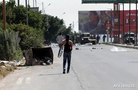 A Palestinian protester hurls stones towards Israeli troops during clashes following a protest in solidarity with Palestinian prisoners held in Israeli jails, at the Hawara checkpoint near the West Bank city of Nablus on...
