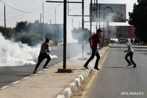 Palestinian protesters run for cover from a tear gas canister fired by Israeli troops during clashes following a protest in solidarity with Palestinian prisoners held in Israeli jails, at the Hawara checkpoint near the W...