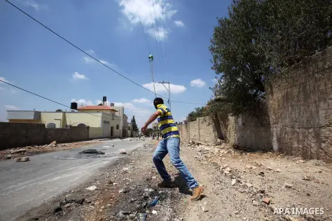 A Palestinian protester uses a slingshot to hurl stones towards Israeli security forces during clashes following a weekly demonstration against the expropriation of Palestinian land by Israel on August 19, 2016, in the v...