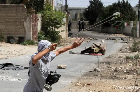 A Palestinian protester uses a slingshot to hurl stones towards Israeli security forces during clashes following a weekly demonstration against the expropriation of Palestinian land by Israel on August 19, 2016, in the v...