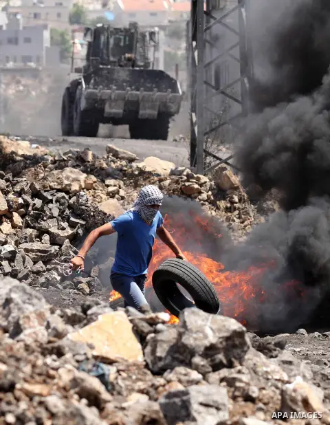 A Palestinian protester carries tires during clashes with Israeli security forces following a weekly demonstration against the expropriation of Palestinian land by Israel on August 19, 2016, in the village of Kfar Qaddum...