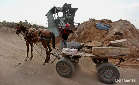 Palestinian men load stones on a cart next to a crater on August 22, 2016 in Beit Lahia in the northern Gaza Strip, following an Israeli airstrike the day before that targeted Hamas positions in the Gaza Strip in respons...