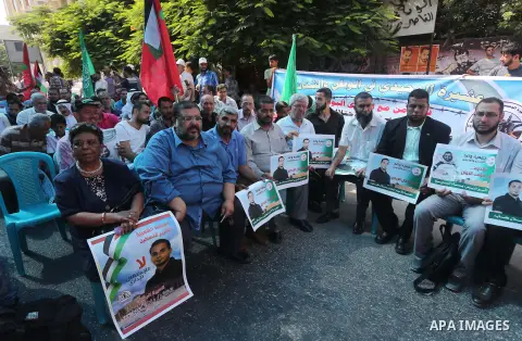 Palestinians hold posters against administrative detention and in support of Palestinian prisoner Bilal Kayed (portrait), who has been fasting for almost two months over his detention without trial, in front of Red Cross...