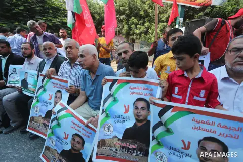 Palestinians hold posters against administrative detention and in support of Palestinian prisoner Bilal Kayed (portrait), who has been fasting for almost two months over his detention without trial, in front of Red Cross...