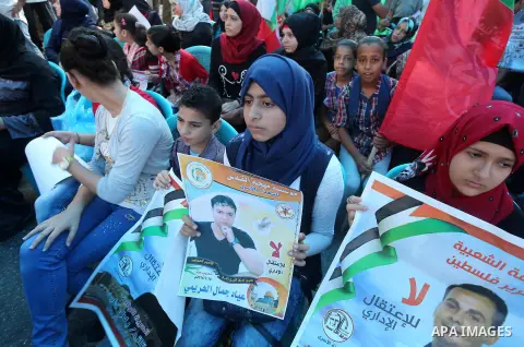 Palestinians hold posters against administrative detention and in support of Palestinian prisoner Bilal Kayed (portrait), who has been fasting for almost two months over his detention without trial, in front of Red Cross...