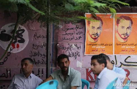 Palestinians hold posters against administrative detention and in support of Palestinian prisoner Bilal Kayed (portrait), who has been fasting for almost two months over his detention without trial, in front of Red Cross...