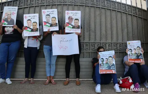 Palestinians hold posters against administrative detention and in support of Palestinian prisoner Bilal Kayed, who has been fasting for almost two months over his detention without trial, outside the United Nations Ramal...