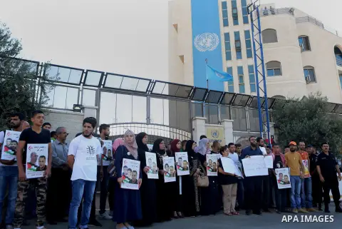 Palestinians hold posters against administrative detention and in support of Palestinian prisoner Bilal Kayed, who has been fasting for almost two months over his detention without trial, outside the United Nations Ramal...
