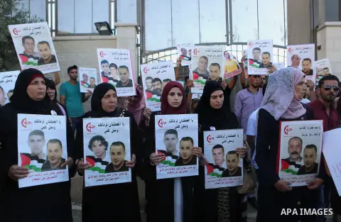 Palestinians hold posters against administrative detention and in support of Palestinian prisoner Bilal Kayed, who has been fasting for almost two months over his detention without trial, outside the United Nations Ramal...