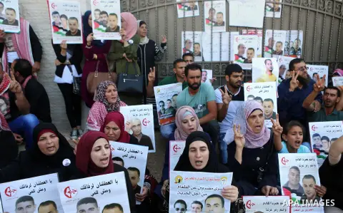 Palestinians hold posters against administrative detention and in support of Palestinian prisoner Bilal Kayed, who has been fasting for almost two months over his detention without trial, outside the United Nations Ramal...